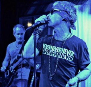 man wearing sunglasses singing into microphone